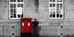 A traditional, red Royal Mail postbox on a street outside a building, illustrating the purpose of service addresses as mail delivery locations