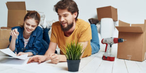 Young couple surrounded by boxes, preparing to move house.