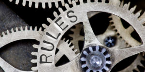 The internal workings of a clock with 'RULES' stamped on a cog wheel, illustrating the concept of articles of association