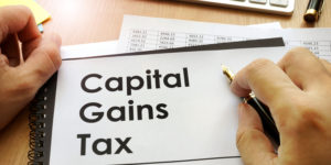 A person's hands holding a document with Capital Gains Tax printed on the front.