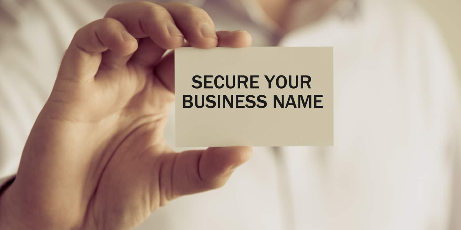 Businessman holding a white card with "SECURE A BUSINESS NAME" displayed in black font.