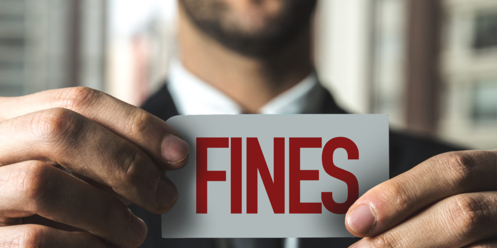 Businessman holding up a white card that displays the word 'FINES' in red text.