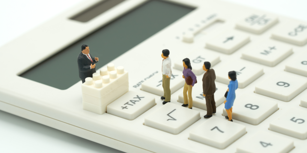 Miniature people standing in a line on a desktop calculator waiting to pay tax.