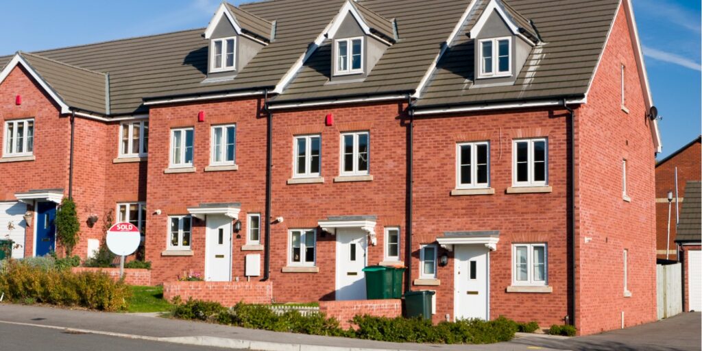 Row of red brick terraced houses with white doors and grey roof tiles.