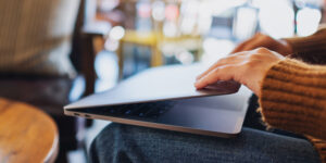 Laptop being closed shut by person in cafe