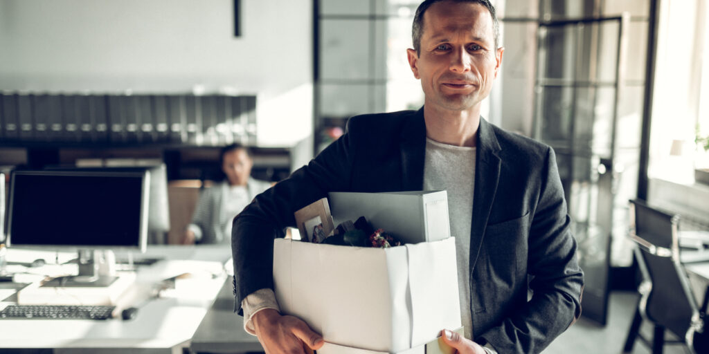 Company director leaving his office with his box of belongings.