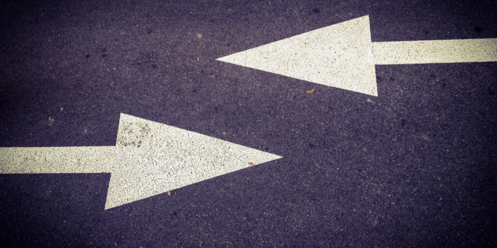 Concrete road with two white arrows pointing in different directions