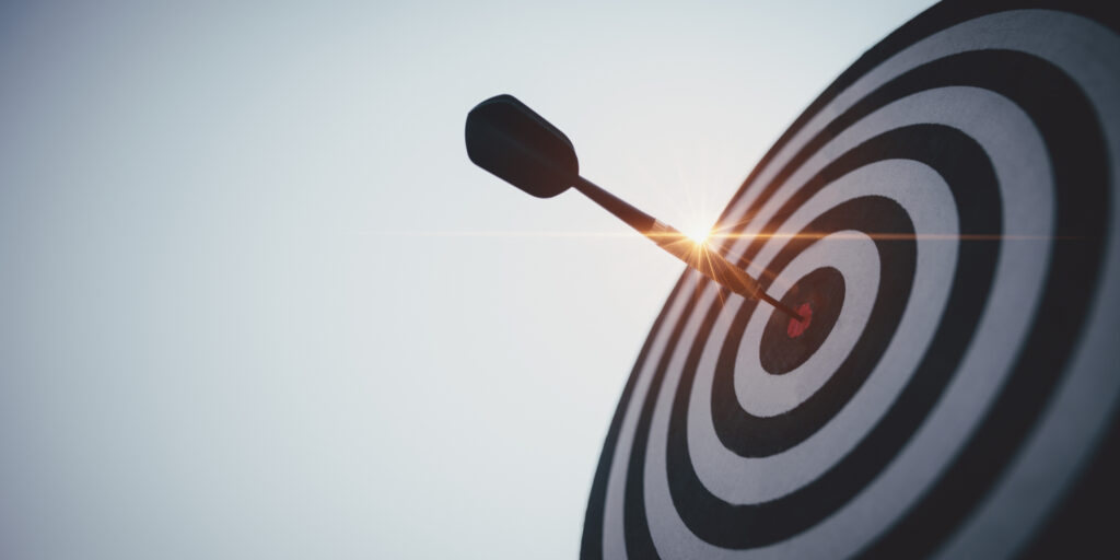 Black and white target with a red dart in its bullseye