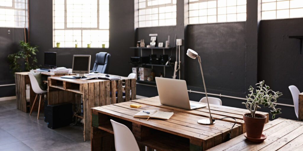 Modern office space with tables and chairs, computers and office supplies with no employees.