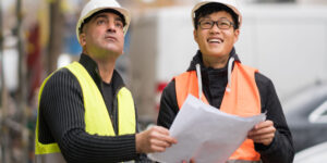 Young Asian apprentice at work on construction site with senior engineer..