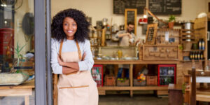 Portrait of a smiling young business owner standing outside her coffee shop, illustrating the trading address concept.