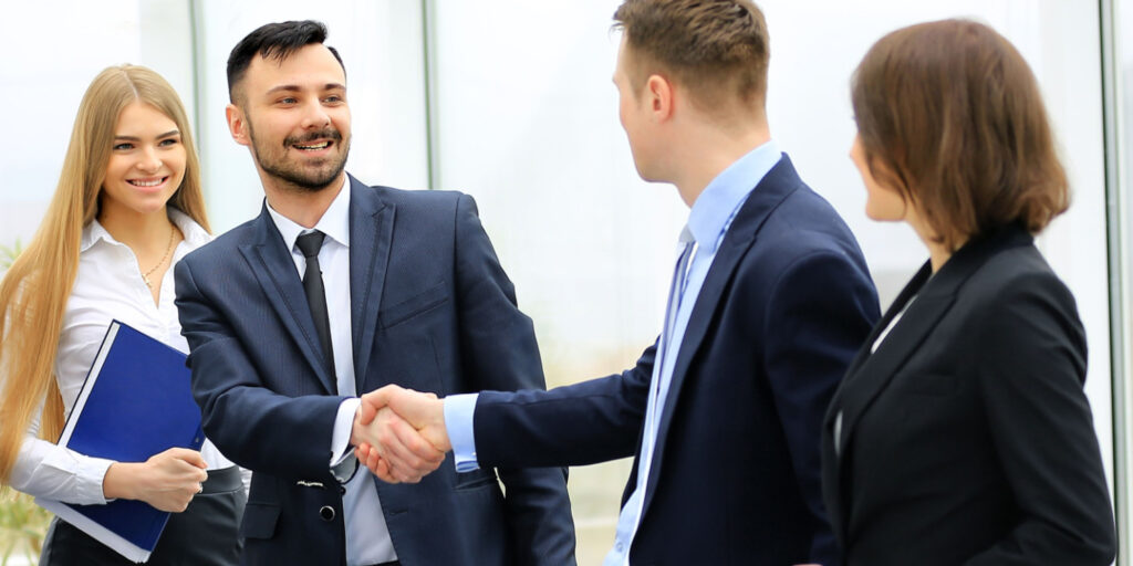 New director being congratulated on his appointment with a handshake from a fellow director.