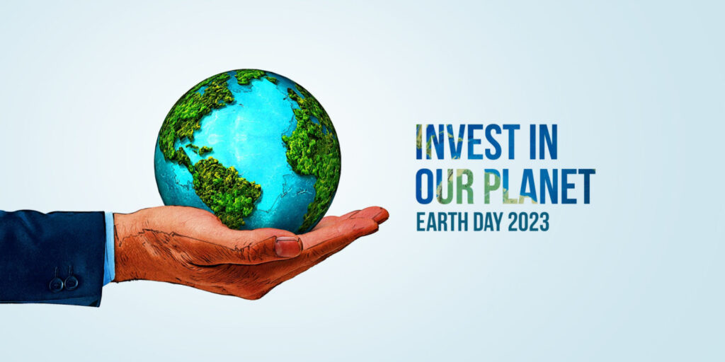 Business owner holding a small world globe in his hand with the headline 'INVEST IN OUR PLANET Earth Day 2023'.