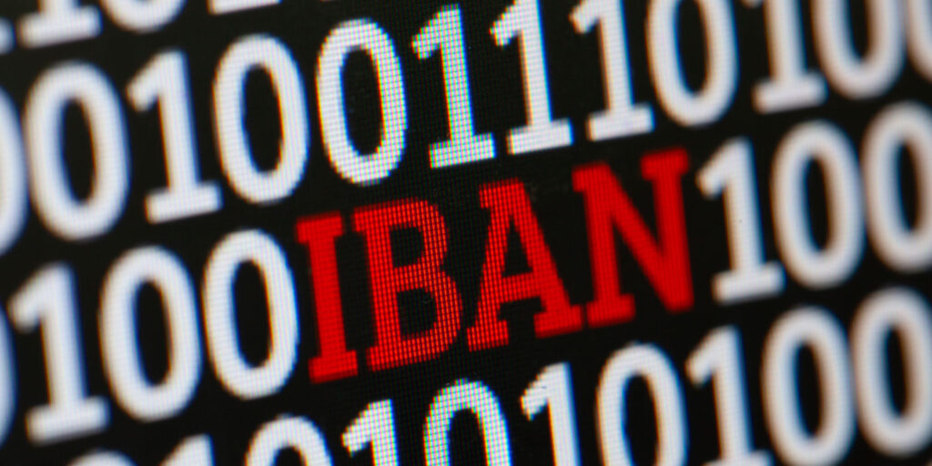 Image of a screen with 'IBAN' displayed in red font, surrounded by binary ones and zeroes in white font against a black background.