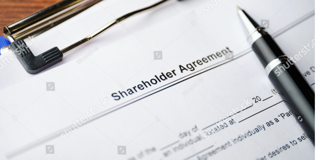 A shareholders' agreement document lying with black pen.