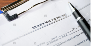 A shareholders' agreement document lying with black pen.