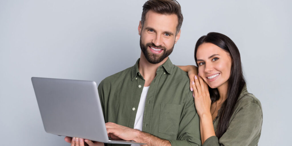 Portrait of cheerful partners using laptop to research the tax implications of transferring shares.