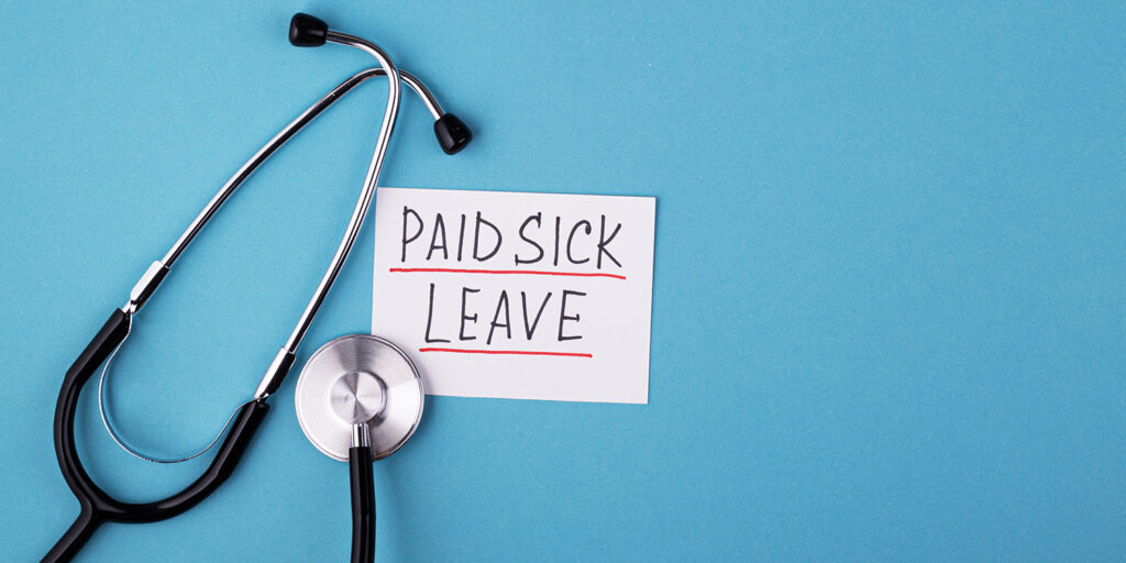 Medical phonendoscope with the inscription 'paid sick leave' on a white card with blue background.