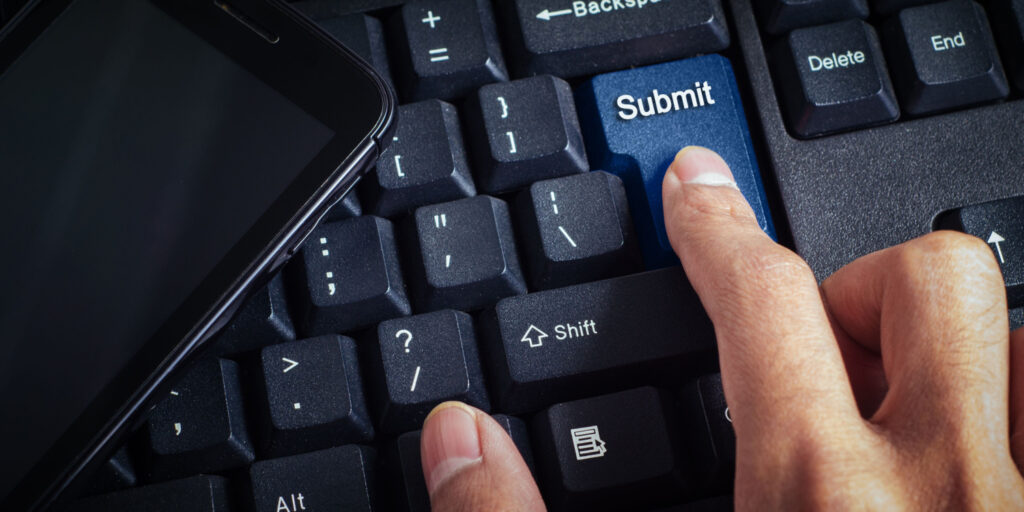 Image of a hand with index finger selecting a blue 'SUBMIT' button on a keyboard.