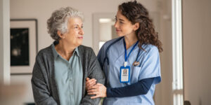 Nurse assisting her old woman patient at nursing home.