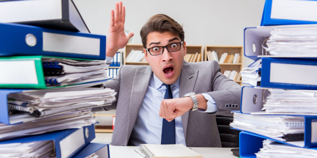 Busy businessman looking at his watched with shocked expression having missed the Self Assessment filing deadline.