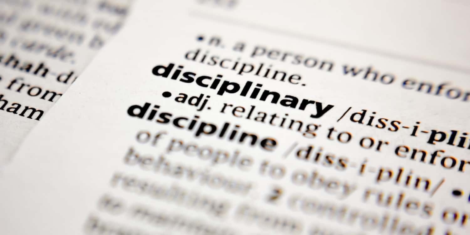 The word 'disciplinary' printed in a dictionary. with the definition of the word partially visible.