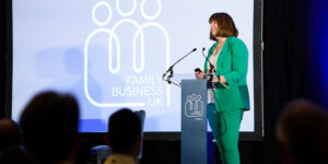 Image of Fiona Graham of Family Business UK, speaking on stage at a conference with the Family Business UK logo displayed in the background.