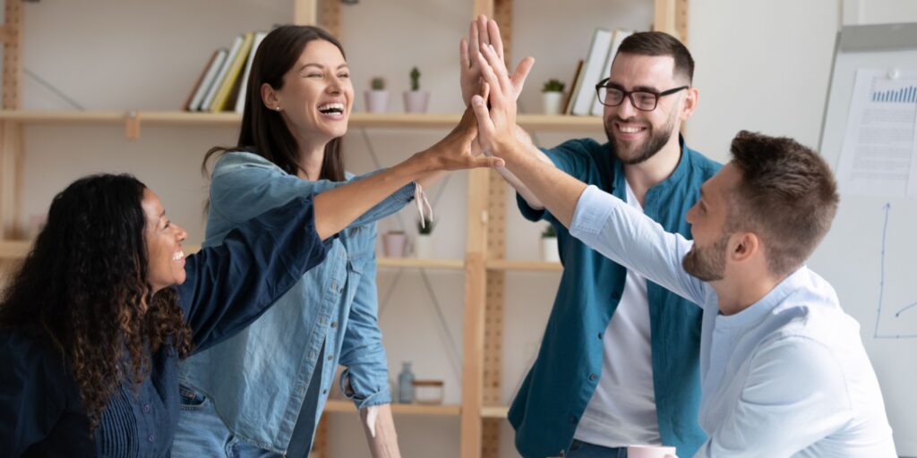 Overjoyed diverse employees giving high five at a meeting celebrating the introduction of their Enterprise Management Incentive (EMI) scheme to their company.