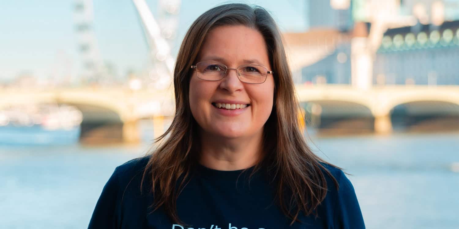 Portrait of Michelle Ovens CBE, founder of Small Business Britain, smiling and standing in London with the River Thames, Westminster Bridge and the London Eye in the background.
