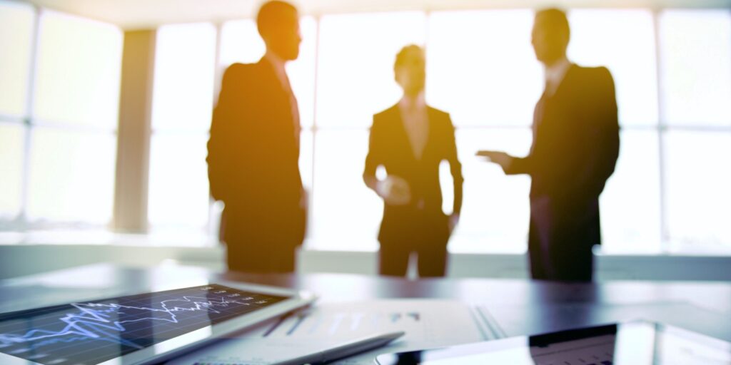 Three directors standing in their boardroom before a meeting.