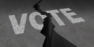 Divided vote concept illustrated by the word VOTE painted on a cracked asphalt floor.