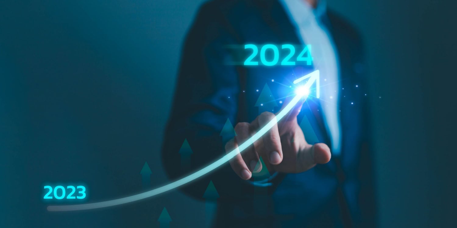 2024 Companies House reigistrations concept image, showing a businessman using a touchscreen displaying a neon arrow trending upwards from 2023 to 2024.