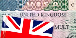 Close-up of a United Kingdom visa with the Union Jack flag sitting on top of it - conceptual image.