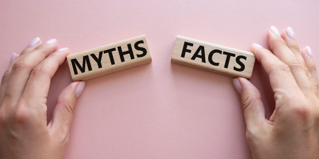 Hands holding 2 wooden blocks with 'MYTHS' and 'FACTS' written on them