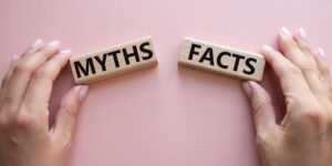 Hands holding 2 wooden blocks with 'MYTHS' and 'FACTS' written on them