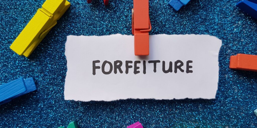 The word FORFEITURE written on a piece of white paper on a blue background.