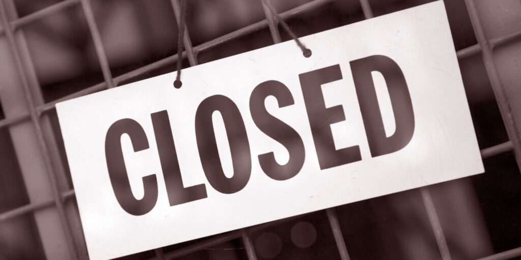 CLOSED sign on a shop door of a business that has been liquidated.