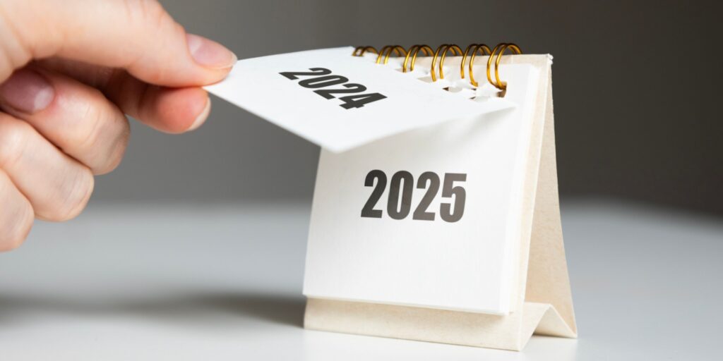 Image of a hand tearing off the '2024' page in a calendar, revealing the next page with '2025'