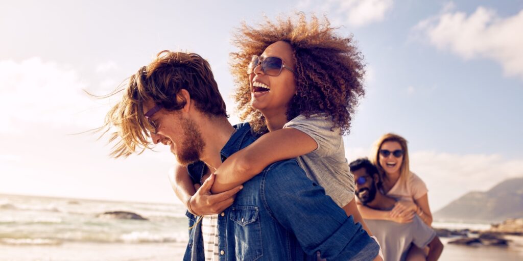 Two happy couples walking along a sunny beach on holiday.