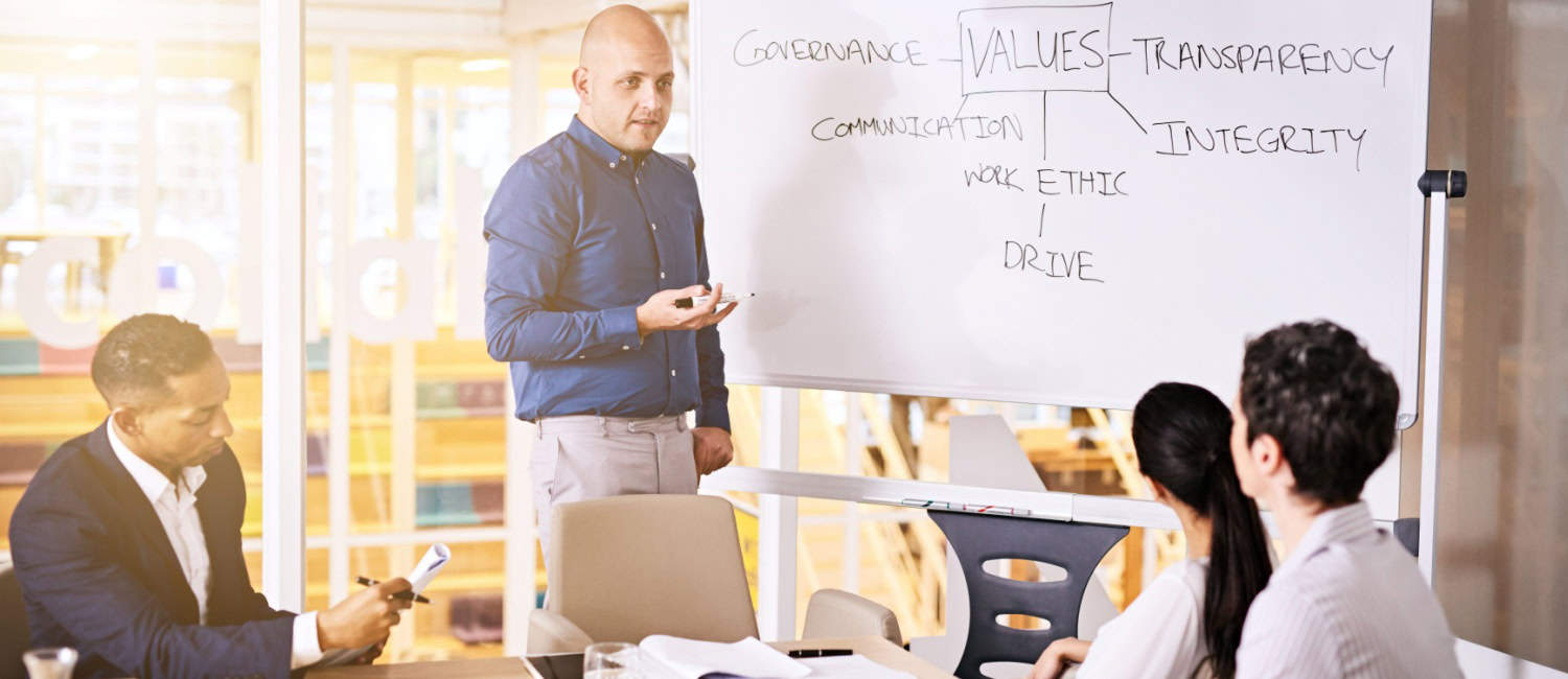 A business owner presents to his team, discussing the organisation's mission, vision, and values.