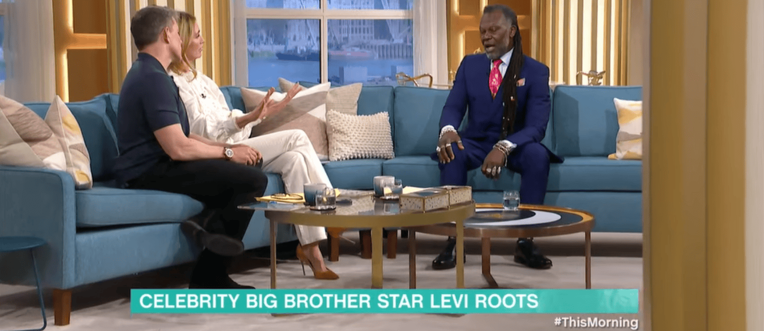 Levi Roots speaking to two presenters on ITV show This Morning. They are sat on comfortable sofas in a television set.