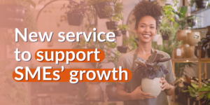 A young, smiling business woman holds plant pots inside her plant shop, with an overlay text reading 'New service to support SMEs' growth'