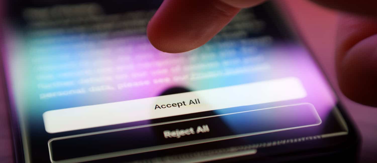 A male finger hovering above an Accept or Reject with cookies policy on a smartphone.